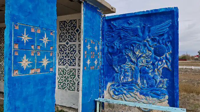 Закрашенный синей краской сказочный барельеф на остановке в районе села Валиханова, Акмолинская область